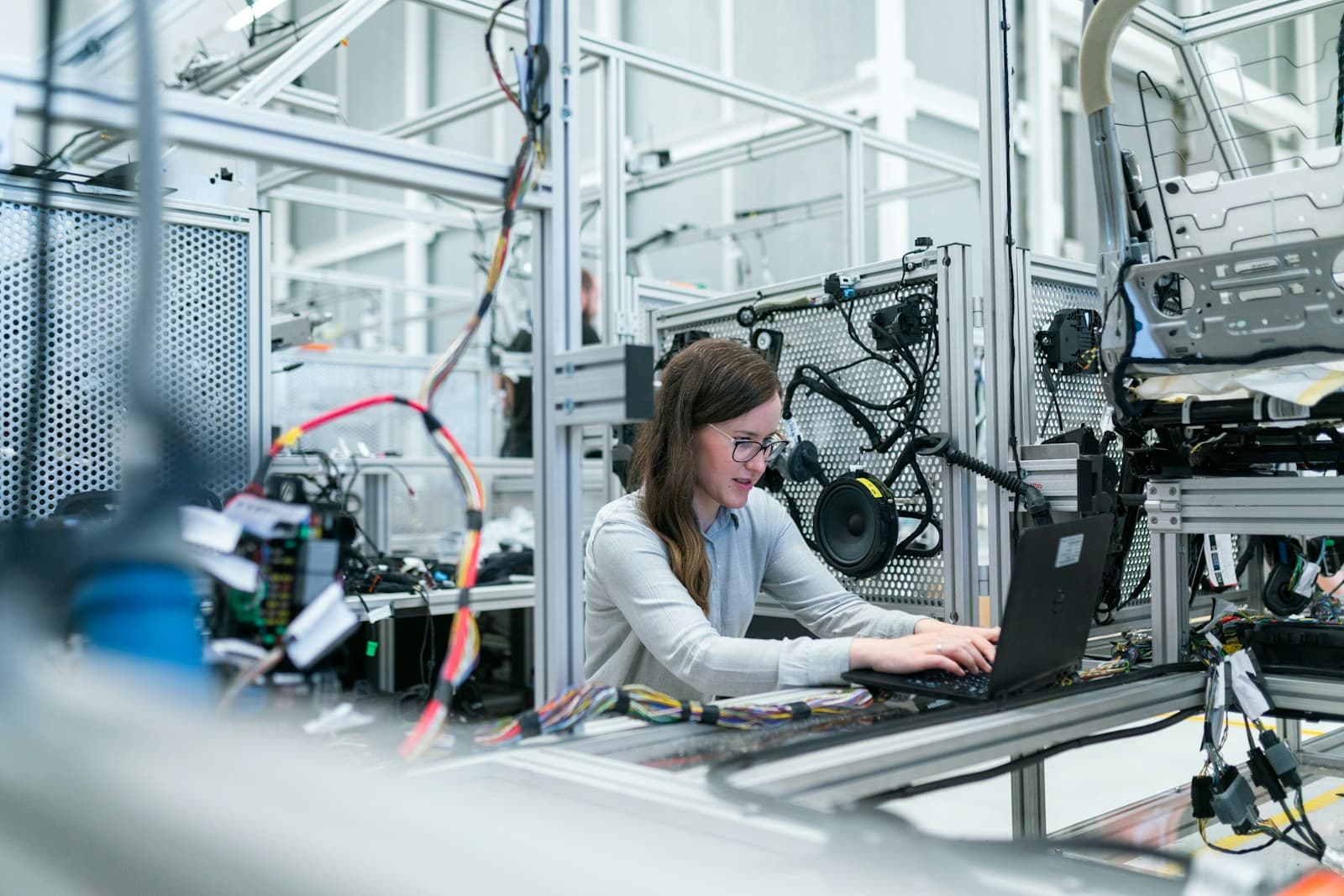 People in safety helmets reviewing work and equipment on a factory production floor.